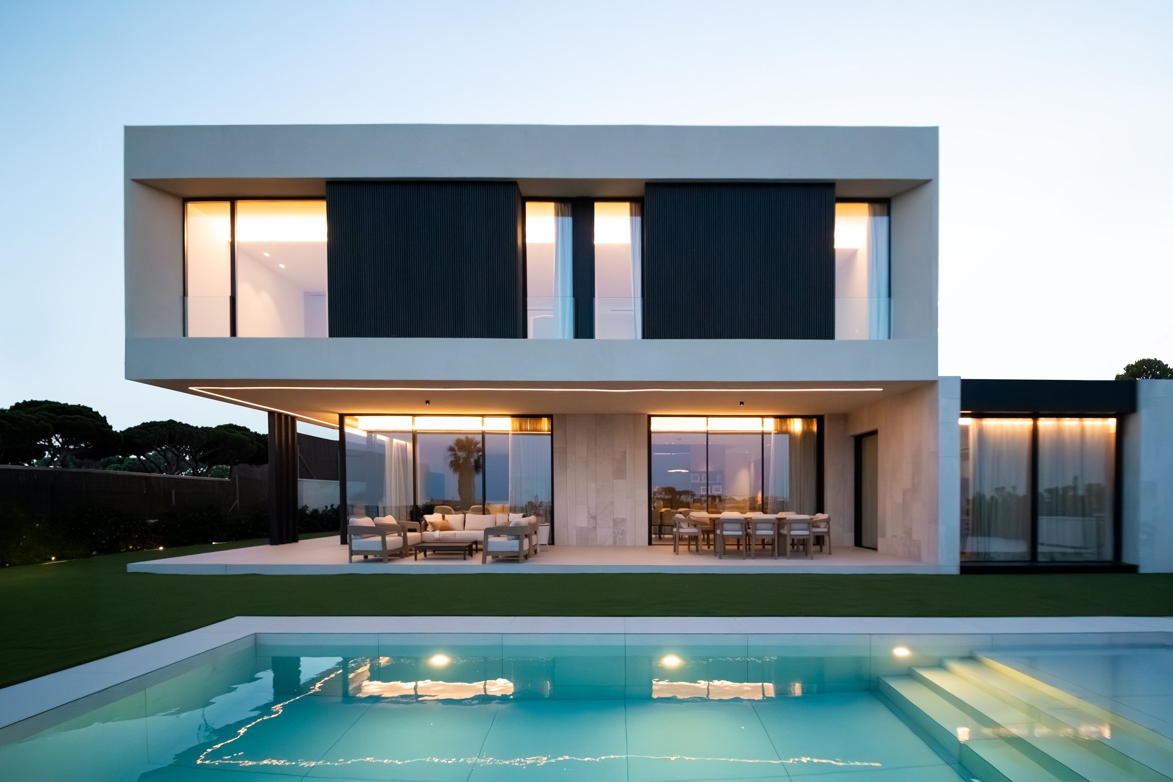Fachada sur de Casa Tormo al atardecer, con el jardín y la piscina