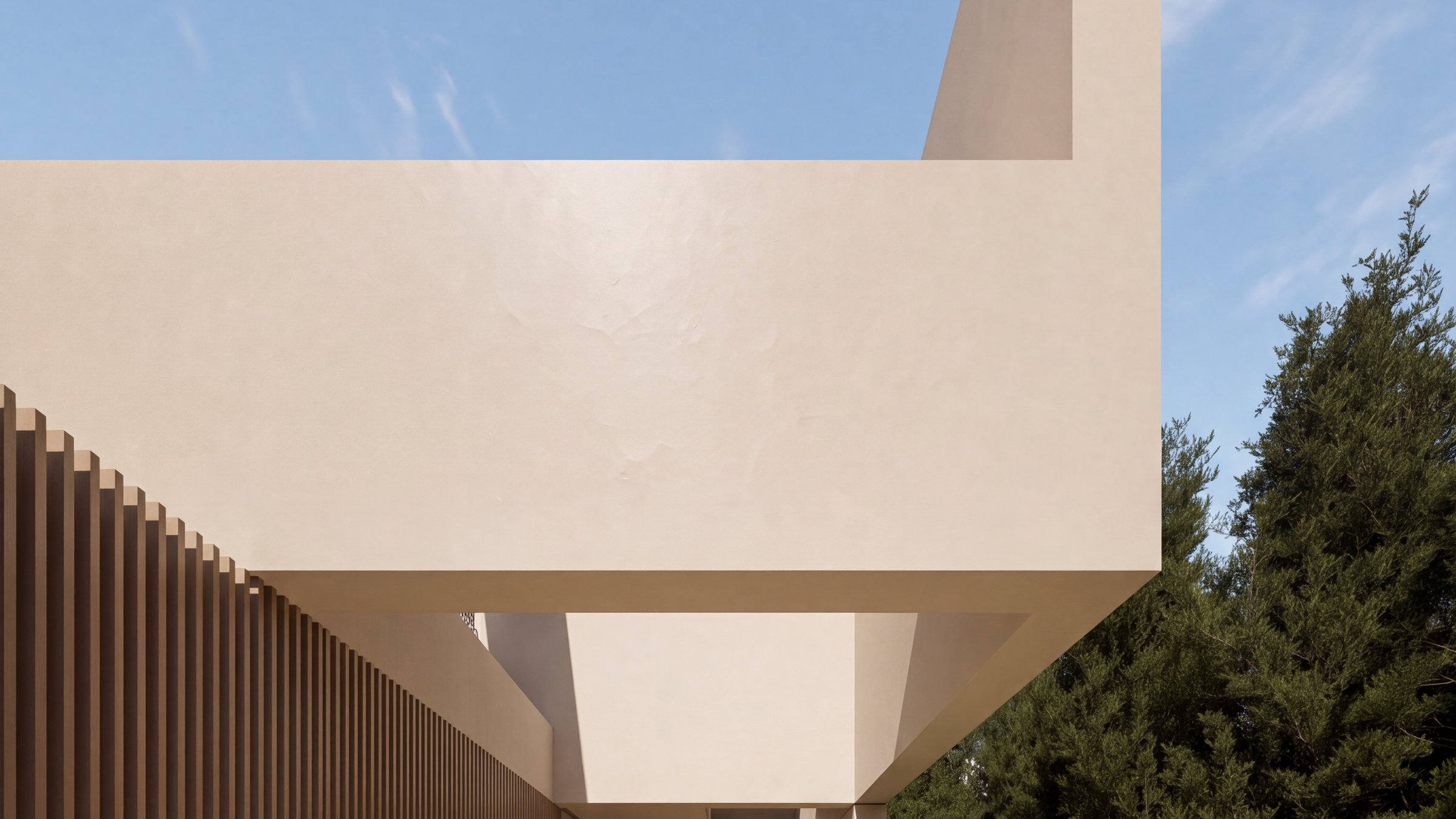 Casa Alma en Bétera: volumen arena en vuelo sobre el acceso, con su testero elevado en un plano inclinado